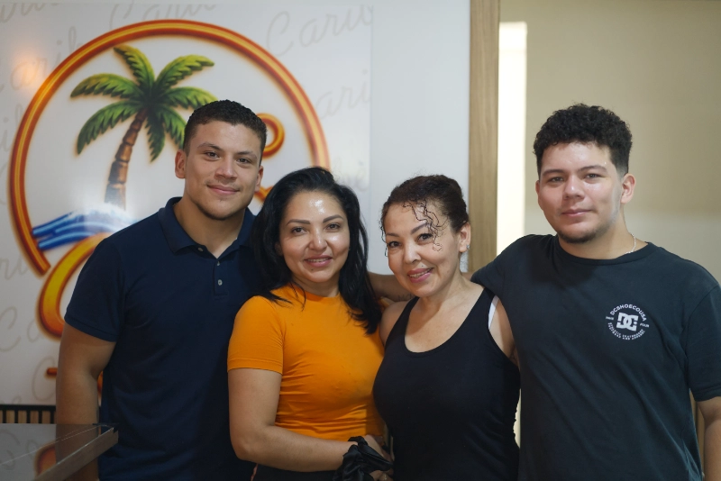Familia de Caribe 2.0 reunida frente al logotipo del restaurante